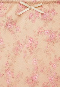 Tifă florală în piersică moale cu flori roz. Prezintă o fundă delicată din panglică crem în centru. Textile moale, texturate.