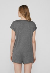 Šedý krátký rukáv top a odpovídající šortky vyrobené z měkké, lehké látky. Kulatý výstřih a volný střih. Minimalistický design bez vzorů.