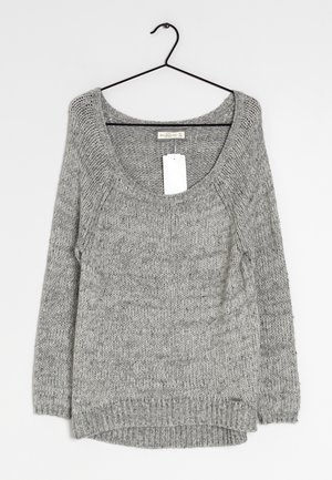 Szary sweter dzianinowy z szerokim dekoltem, długimi rękawami i nieco dłuższym tyłem. Posiada metkę zwisającą z okolicy szyi.