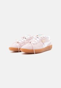 Adidași din suede roz cu accente albe, vârf rotund și talpă texturată din cauciuc. Prezintă șireturi din panglică și detalii cu logo pe lateral.