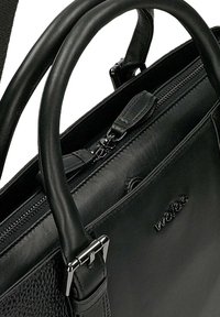 Schwarze Lederhandtasche mit strukturiertem Oberflächen, doppelten Griffen, Reißverschluss und silbernen Hardware-Akzenten. Logo auf der Vorderseite geprägt.