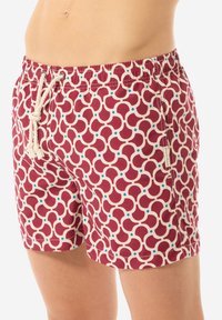 Pantaloni da bagno rossi con un motivo geometrico in crema e dettagli blu. Presentano un elastico in vita con cordoncino e tasche laterali.