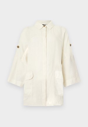 Εκρού λινό σακάκι με μακριά μανίκια, γιακά με κουμπιά, μπροστινές τσέπες με καπάκι και ρυθμιζόμενα κουμπιά στα μανίκια πάνω σε απλό φόντο.