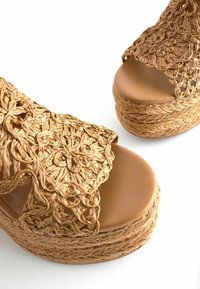 Woven raffia platform sandals z otwartym palcem, z teksturowanym wierzchem i gładką, brązową wkładką. Podeszwa jest owinięta sznurkiem i masywna.