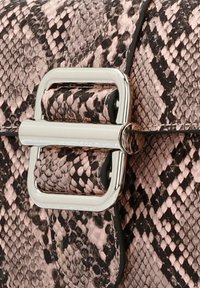 Gestructureerde handtas in roze slangenprint met een zilveren vierkant sluiting en zwarte randafwerking, die een moderne, slanke uitstraling benadrukt.