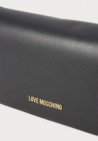 Black faux leather clutch bag with a textured finish. Features a prominent gold "LOVE MOSCHINO" logo. Rectangular shape with a smooth outline.
