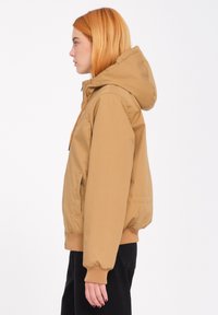 Lichtbruine ritssluitingjas met capuchon, elastische manchetten en een zijzak, met een gladde textuur en een relaxte pasvorm.