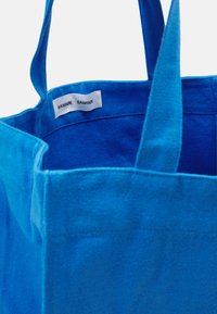 Bolsa de tela azul con dos asas resistentes, que presenta un interior azul claro y una etiqueta cosida que muestra "SAMSØE SAMSØE."