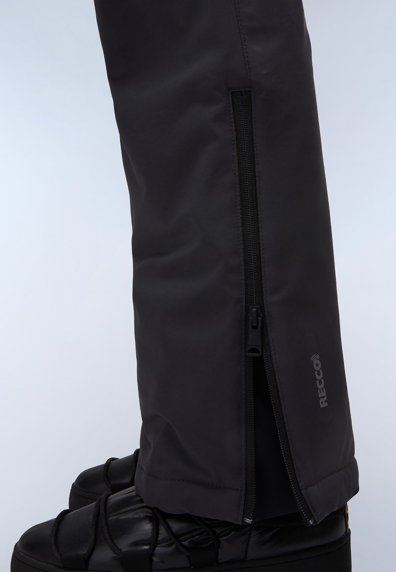 Cubrezapatillas impermeables negras con cremalleras laterales, fabricadas en material sintético, con la marca RECCO, usadas sobre botas negras aislantes.