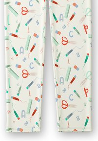 Leggings con una stampa a tutto campo di articoli di cancelleria come forbici, matite e righelli in rosso, verde, blu e rosa su uno sfondo crema.