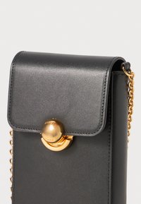 Svart faux skinn crossbody-veske med en gylden, sirkulær lås og kjede-rem; har klaffelukking og glatt tekstur.