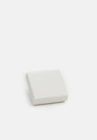 Firkantet, myk teksturert, lys grå boks med en subtil preget logo på toppen, med glatte kanter og minimalistisk design.
