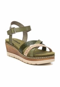 Sandalias de cuña verdes y beige con tiras cruzadas. Correa ajustable en el tobillo, detalles perforados y una plantilla acolchada sobre una suela texturizada.