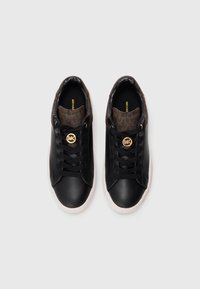 Svart lave sneakers med hvite såler, svarte snører og brunt mønstrete stoff rundt hælen og tungen, med gull sirkulære logo detaljer.