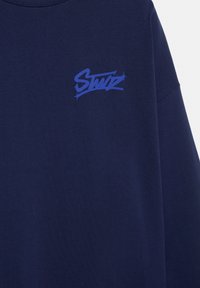 Maglietta di cotone blu navy con un piccolo logo blu stilizzato sul petto. Scollo tondo, texture morbida e vestibilità comoda.