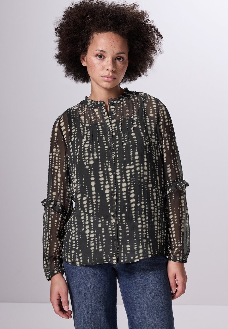 Schwarze durchsichtige Bluse mit einem gemusterten hellbeigen Design, ausgestattet mit einem Rüschenkragen, einer Knopfleiste und langen Ärmeln mit gerafften Manschetten.