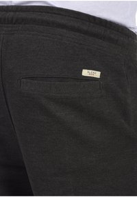 Jogging noir texturé avec une poche arrière arborant un petit label "BLEND". Taille élastique pour le confort. Design simple et pratique.