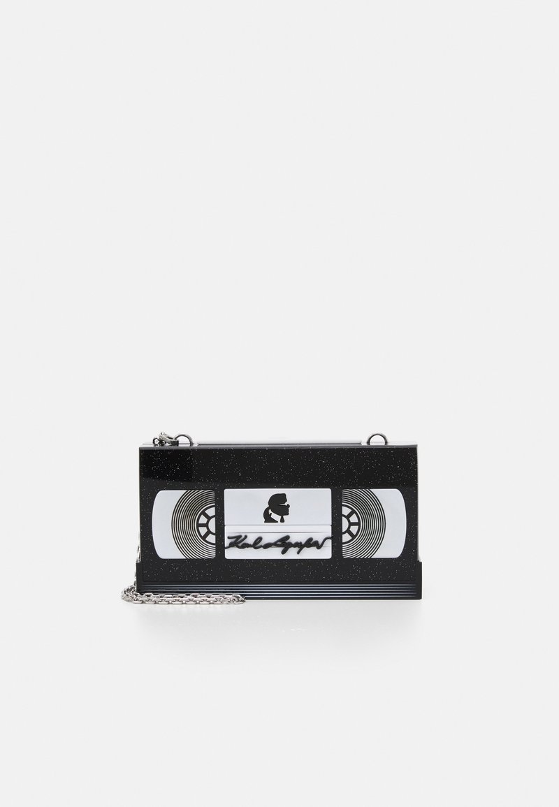Sac à main rectangulaire noir en forme de cassette VHS avec une bandoulière chaîne argentée et un petit logo silhouette sur le devant.