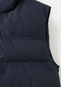 Mornarsko modra pufasta brezrokavnik z visokim ovratnikom, brezrokavnim oblikovanjem, gladko teksturo in horizontalnim prešitim vzorcem za izolacijo. Enostavna šivana podrobnost.