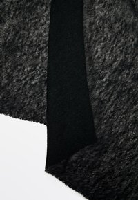 Czarna tkanina z przezroczystą, teksturowaną powłoką oraz gładko tkanym, jednolitym czarnym fragmentem. Krawędzie są surowe, z miękkim, płynącym drapowaniem.