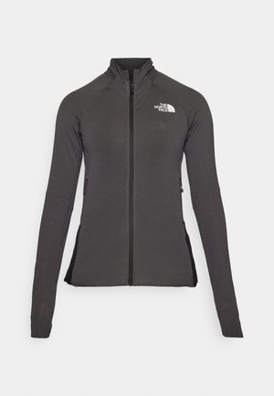 Svart zip-up jacka med hög krage, texturerad tyg och långa ärmar. Har The North Face-logotypen på övre vänstra sidan.