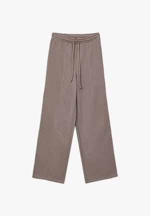 Pantaloni sportivi a gamba larga di colore taupe chiaro, realizzati in tessuto morbido. Presentano un elastico in vita con cordino e cuciture verticali sulle gambe.