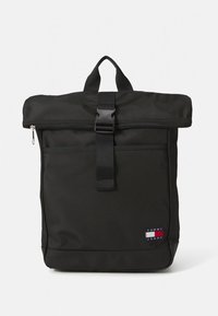 Black roll-top backpack made of durable fabric, featuring a front zip pocket, adjustable strap, and a Tommy Jeans logo patch.