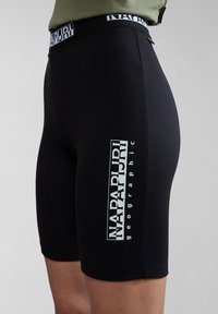 Černé strečové šortky vyrobené z měkkého materiálu, s bílým logem "NAPAPIJRI" na boku a elastickým pasem se značkováním.