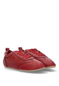Zapatos de piel roja con superficie texturizada, punta redondeada y ribete negro. Cuentan con cordones redondos y suelas de goma de perfil bajo.