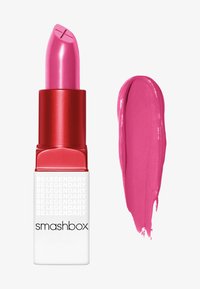 Smashbox läppstift i en röd tub med vit text, med en ljusrosa läppstiftspets och en matchande krämfärg.