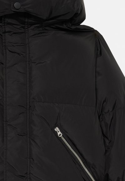 Giacca a vento nera con cappuccio. Presenta una tasca con zip, una texture a quadranti, un tessuto liscio e lucido, e un design a vestibilità rilassata.