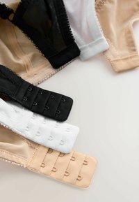 Quatre soutiens-gorge en noir, blanc et tons chair, avec des tissus en maille et lisse. Les fermetures présentent plusieurs crochets de différentes couleurs et textures.