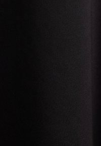 Texture de tissu noir avec un motif de tissage diagonal subtil et un éclairage doux mettant en valeur les détails de la surface.