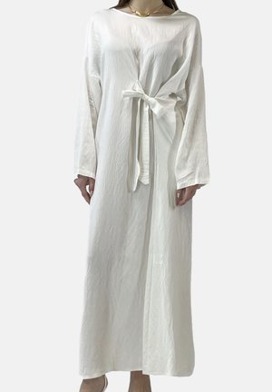 Lang hvid kjole lavet af letvægtsstof, med en løs pasform, bindebælte i taljen og lange ærmer. Simpelt, tekstureret design.