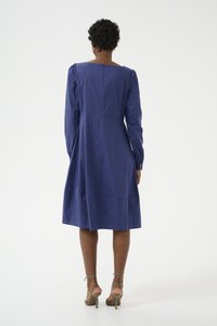 Vestido azul con mangas largas y escote cuadrado, con un detalle fruncido en los hombros y un dobladillo a la altura de la rodilla.