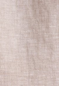 Tissu en lin beige avec une texture tissée montrant des fibres naturelles irrégulières et de légères variations de couleur.