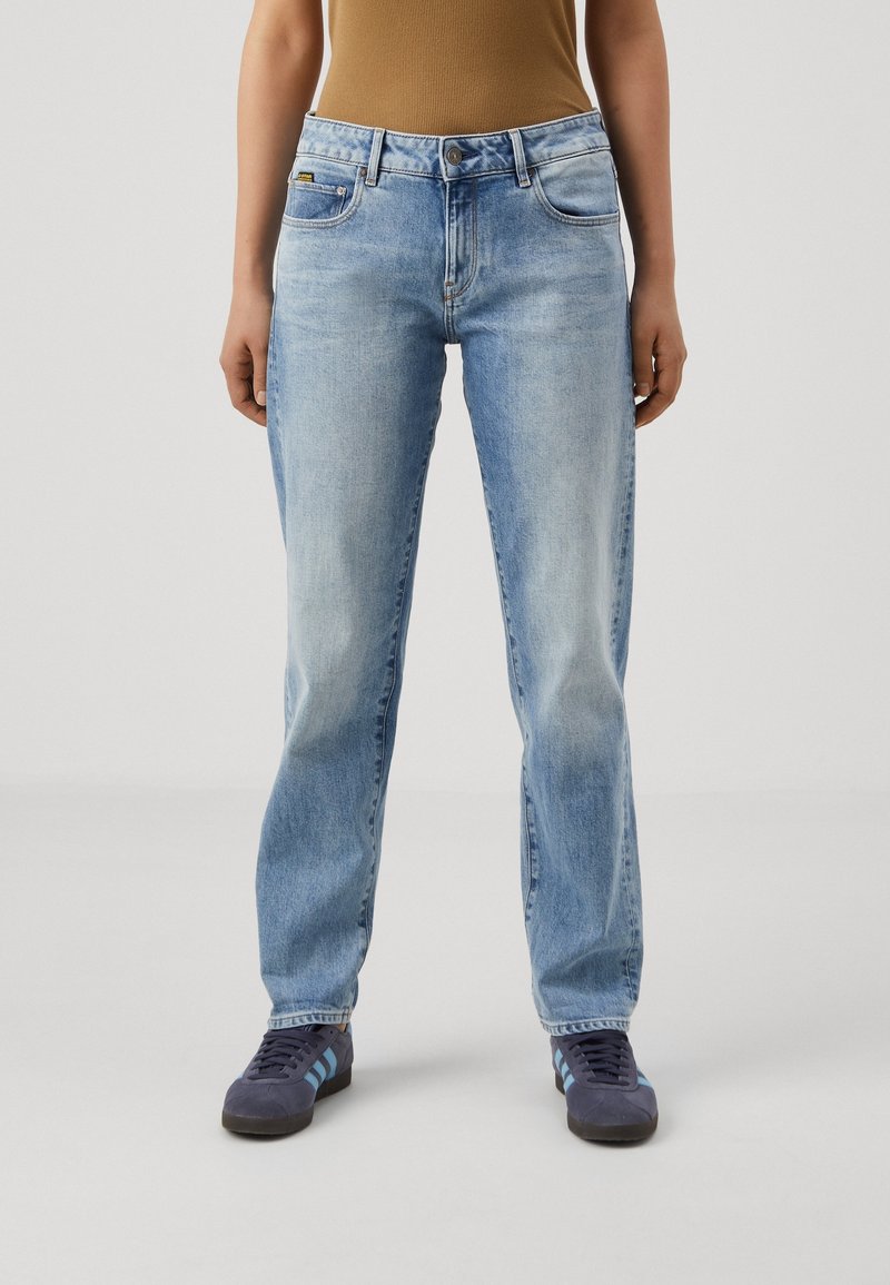 Ljust blå jeans med en klassisk femficksdesign, rak benpassform och subtil sliten textur. I kombination med marinblå skor.