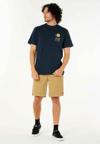 Navy blue cotton t-shirt with front graphic featuring palm trees and text. Worn with beige corduroy shorts and black sneakers.