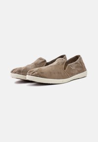 Könnyen felvehető, világosbarna anyagú slip-on cipő, gyűrött textúrával, fehér gumitalppal és oldalsó rugalmas panelekkel a könnyű viseletért.