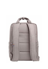 Grå tygryggsäck med vadderad baksida och remmar, med en texturerad frampanel. Liten dragkedjeficka på sidan och logotypdetalj.