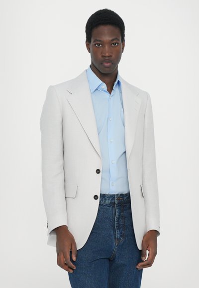 Sacou gri deschis cu două butoane negre, asortat cu o cămașă bleu și blugi albaștri. Textură netedă, design croit, potrivire modernă.