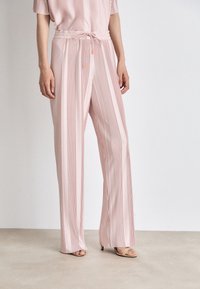 Helle rosa, plissierte weit geschnittene Hose mit einem Kordelzugbund. Der Stoff hat eine glatte Textur und vertikale Streifen für zusätzliche Details.