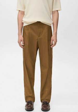 Pantalon marron à jambes larges en tissu lisse. Caractérisé par des plis avant et des poches latérales, associé à des chaussures à lacets marron foncé.
