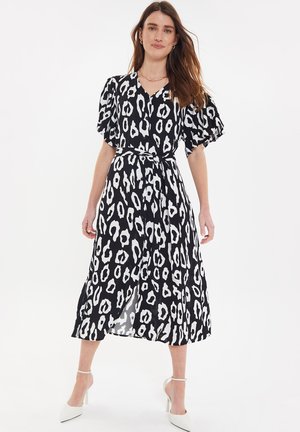 Zwarte en witte luipaardprint jurk met een V-hals, korte pofmouwen, een tailleband en een vloeiende, enkel lange rok.