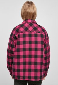 Pink and black checkered flannel shirt with a collar, button cuffs, and a relaxed fit. The back features a visible seam and plaid pattern.