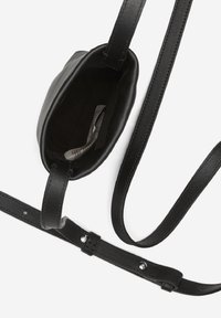 Czarna skórzana torba na ramię o prostokątnym kształcie. Posiada jeden pasek i gładką powierzchnię. Wewnętrzna podszewka jest ciemna, a widoczna jest metka.