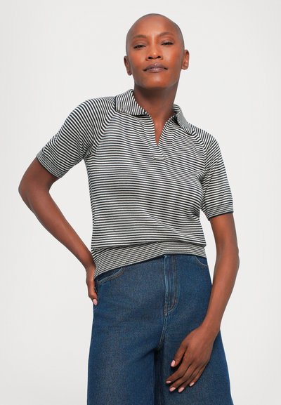 Striped polo shirt in black and white, short sleeves, with a collar and ribbed hem, paired with high-waisted blue denim wide-leg pants.