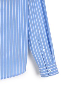 Jasnoniebieska koszula w paski z białymi pionowymi paskami, z zapięciem na guzik przy mankietach i kołnierzykiem w szpic. Wykonana z gładkiego materiału.