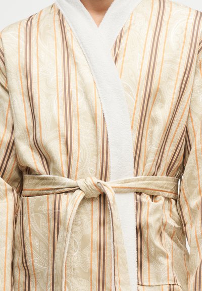 Personne portant un peignoir rayé beige avec un motif paisley, noué à la taille, ne montrant que la poitrine et la partie médiane.