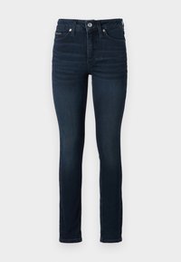 Σκούρες μπλε ψηλόμεσες τζιν παντελόνες από τζιν, με στενή εφαρμογή και απαλές φθορές. Απλός μεταλλικός κουμπί και φερμουάρ στη μέση.